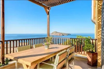 a wooden table on a balcony with a view of the ocean at Golden View Luxury Villa Platanias in Plataniás