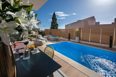 a patio with a table and a swimming pool at Flos Apartments in Korakiaí