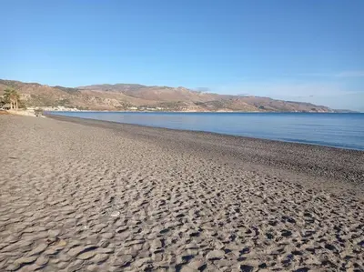 a sandy beach with the ocean and mountains in the background at Micro_Ble vacation home in Ropanianá