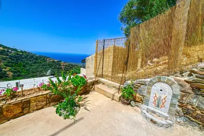 a stone wall with flowers and a stone bench at Traditional Stone House with Mountain & Sea Views 