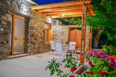 a patio with a table and chairs under a wooden pergola at Traditional Stone House with Mountain & Sea Views 