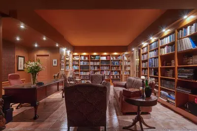 a library with a couch and chairs and bookshelves at Villa Kapodistria in Kallithea-Voukolies