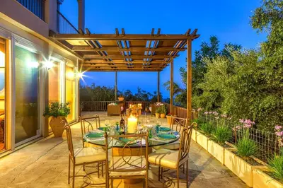 a patio with a table and chairs and a pergola at Villa Kapodistria in Kallithea-Voukolies