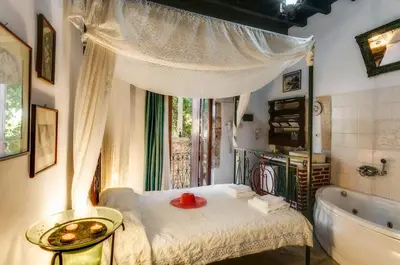 a bathroom with a tub and a bed and a window at IFIGENIA ROOMS BY MARIOS in Chania Town