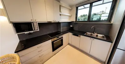 a kitchen with white cabinets and a sink and a microwave at Mitos Villas in Gerani Chanion