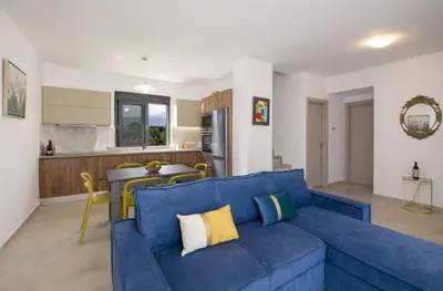 a living room with a blue couch and a kitchen at Almyrida Hills Villas in Koprána