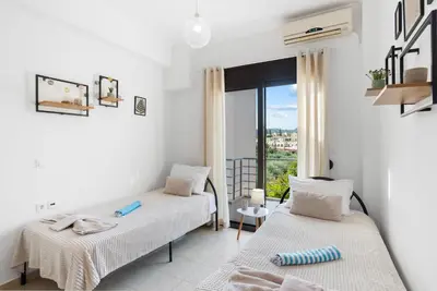 two beds in a room with a window at Almyrida Bay View House II BY APOKORONAS-VILLAS in Almirida