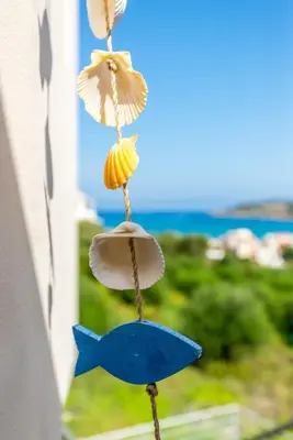three seashell ornaments are hanging on a window at Almyrida Bay View House II BY APOKORONAS-VILLAS in Almirida