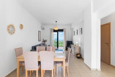 a dining room and living room with a table and chairs at Almyrida Bay View House II BY APOKORONAS-VILLAS in Almirida