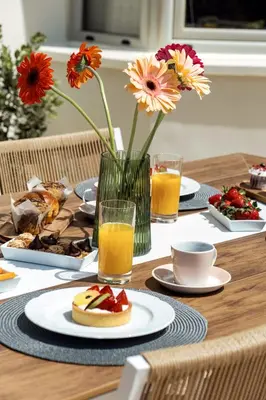 a table with plates of food and a vase of flowers at La Casa Di Fiori Stylish Holiday Home in Plataniás