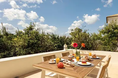a wooden table on a balcony with a meal on it at La Casa Di Fiori Stylish Holiday Home in Plataniás