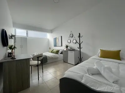 a white bedroom with a bed and a desk at AIOLOS Chania center luxury apartment near the garden in Chania Town