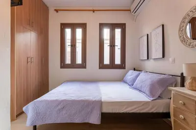 a bedroom with a bed with white sheets and two windows at Splatzia old town house in Chania Town
