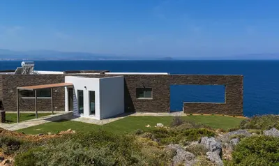 a brick house on the edge of the ocean at Luxury seafront design villa Kyma in Tersanas Owner listing in Tersanas