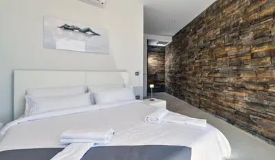 a bedroom with a large bed and a brick wall at Luxury seafront design villa Kyma in Tersanas Owner listing in Tersanas