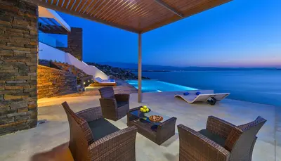 a patio with a table and chairs and a swimming pool at Luxury seafront design villa Kyma in Tersanas Owner listing in Tersanas