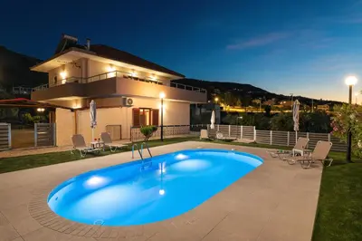 a swimming pool in front of a house at night at Garden House with Pool, 10min to center in Nerokoúros