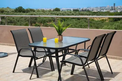 a table with three chairs and two glasses of orange juice at Garden House with Pool, 10min to center in Nerokoúros