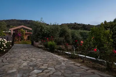 a stone path in a garden with flowers at Garden House with Pool, 10min to center in Nerokoúros