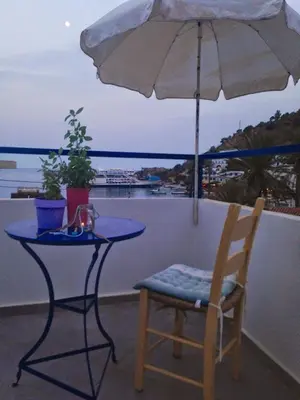 a table and a chair and an umbrella on a balcony at Sofia Rooms in Loutro