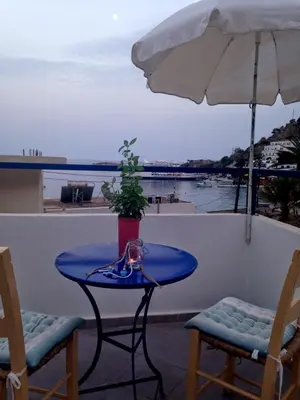 a table and chairs on a balcony with an umbrella at Sofia Rooms in Loutro