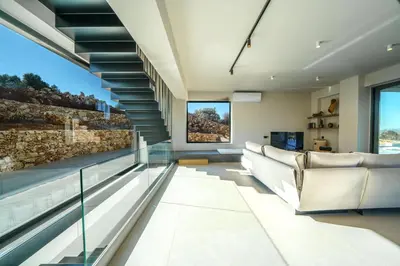 a living room with a couch and a glass staircase at In Vivo Villa - Breathtaking View -90sqm Heated Infinity Pool in Áyios Pávlos