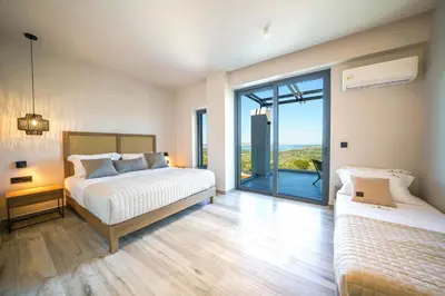 a bedroom with two beds and a large window at In Vivo Villa - Breathtaking View -90sqm Heated Infinity Pool in Áyios Pávlos
