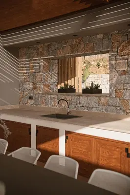 a kitchen with a sink and a stone wall at Villa Aora Falassarna Beach I New luxury villa with infinity pool in Falasarna
