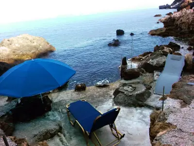 a blue chair and an umbrella next to the water at 2 annexed apartments -Private place to swim-large terrace- Unlimited view in Ravdhoúkha