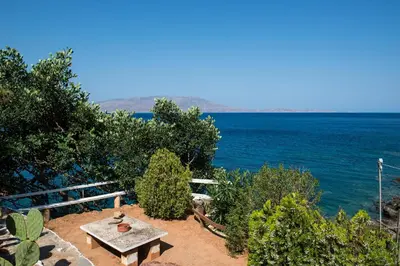 a picnic table sitting on the side of the ocean at 2 annexed apartments -Private place to swim-large terrace- Unlimited view in Ravdhoúkha