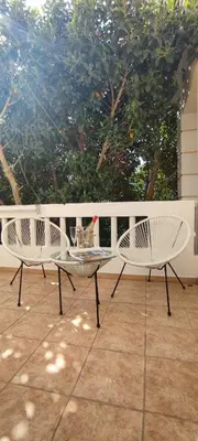 two white chairs and a table on a patio at Villa Ithaca in Varípetron