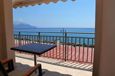 a balcony with a table and a view of the ocean at Corali Studios in Palaiochóra