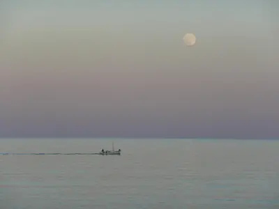 a boat on the water with the moon in the sky at Corali Studios in Palaiochóra