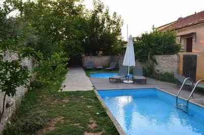 a backyard with a swimming pool with an umbrella and chairs at Venetian Cistern Villa in Kalamítsion Alexándrou