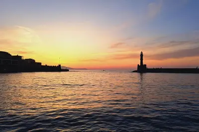 a sunset over a body of water with a lighthouse at Beautiful house in the old town of Chania- 4 rooms in Chania Town