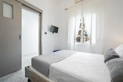 a white bedroom with a bed and a window at Elie's House next to the beach in Chania Town
