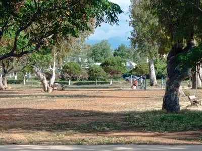 a park with a tree and a bench and a playground at Villa Ammos in Daratso