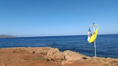 a yellow and blue flag on the edge of the ocean at Villa Ammos in Daratso