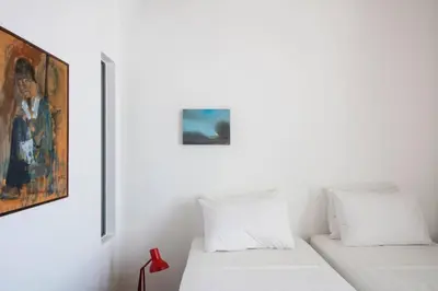 two beds in a white room with a painting at Elorhouse in the charming neighborhood of KoumKapi in Chania Town