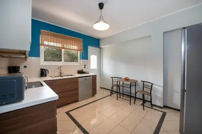 a kitchen with blue walls and a table and chairs at Green Hill Villa in Daratso