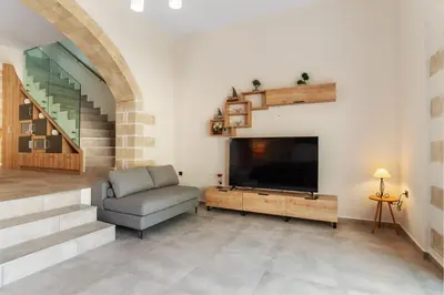 a living room with a television and a chair and stairs at Brand new Villa Volakas BY APOKORONAS VILLAS in Gavalochori
