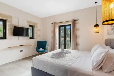 a bedroom with a bed and a tv and a chair at Brand new Villa Volakas BY APOKORONAS VILLAS in Gavalochori