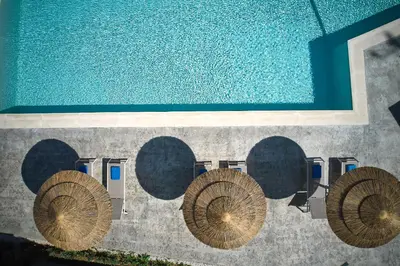a swimming pool with four wooden spheres on the wall at Villaggio Mare Suites in Kalamaki Chanion