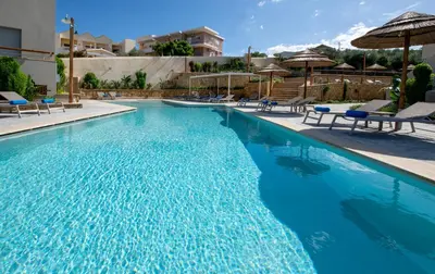 a large swimming pool with chairs and umbrellas at Villaggio Mare Suites in Kalamaki Chanion