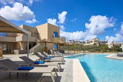 a row of lounge chairs next to a swimming pool at Villaggio Mare Suites in Kalamaki Chanion