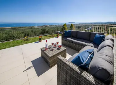a patio with a couch and a table with wine glasses at Iliada by Vintage Travel in Maleme