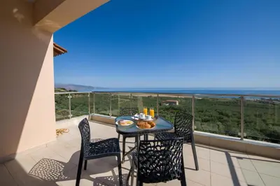 a balcony with a table and chairs and the ocean at Iliada by Vintage Travel in Maleme