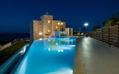 a swimming pool in front of a villa at night at Iliada by Vintage Travel in Maleme