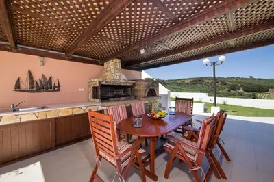 a dining room with a table and chairs and a kitchen at Iliada by Vintage Travel in Maleme