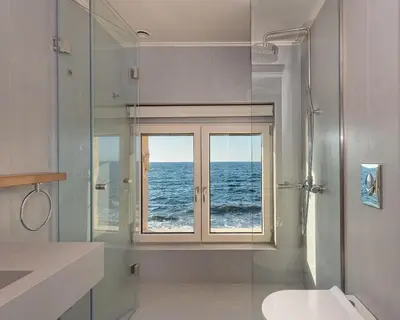 a bathroom with a view of the ocean through a window at Hippocampo Waterfront Villa in Chania Town